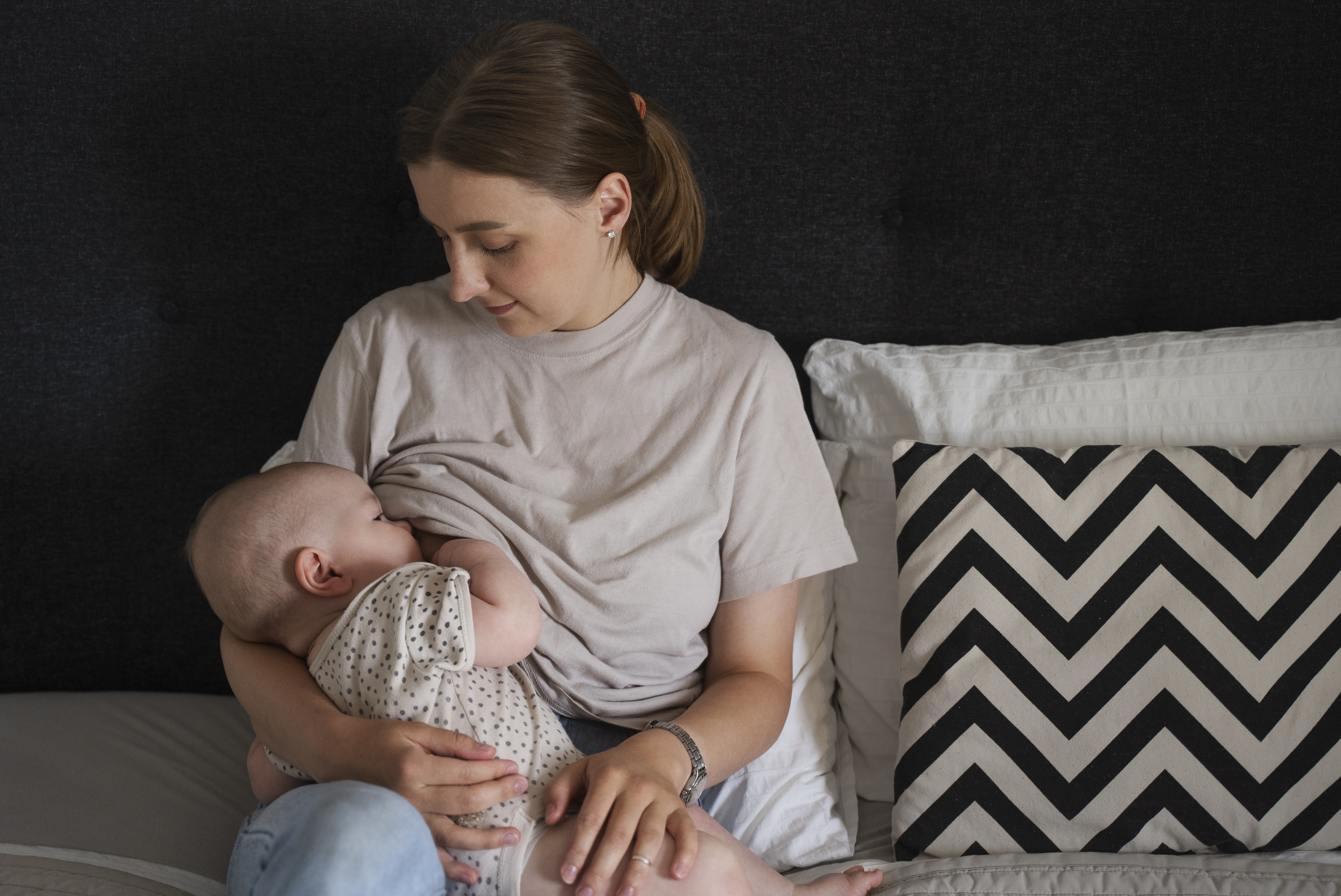 Mother breastfeeding her baby on the bed