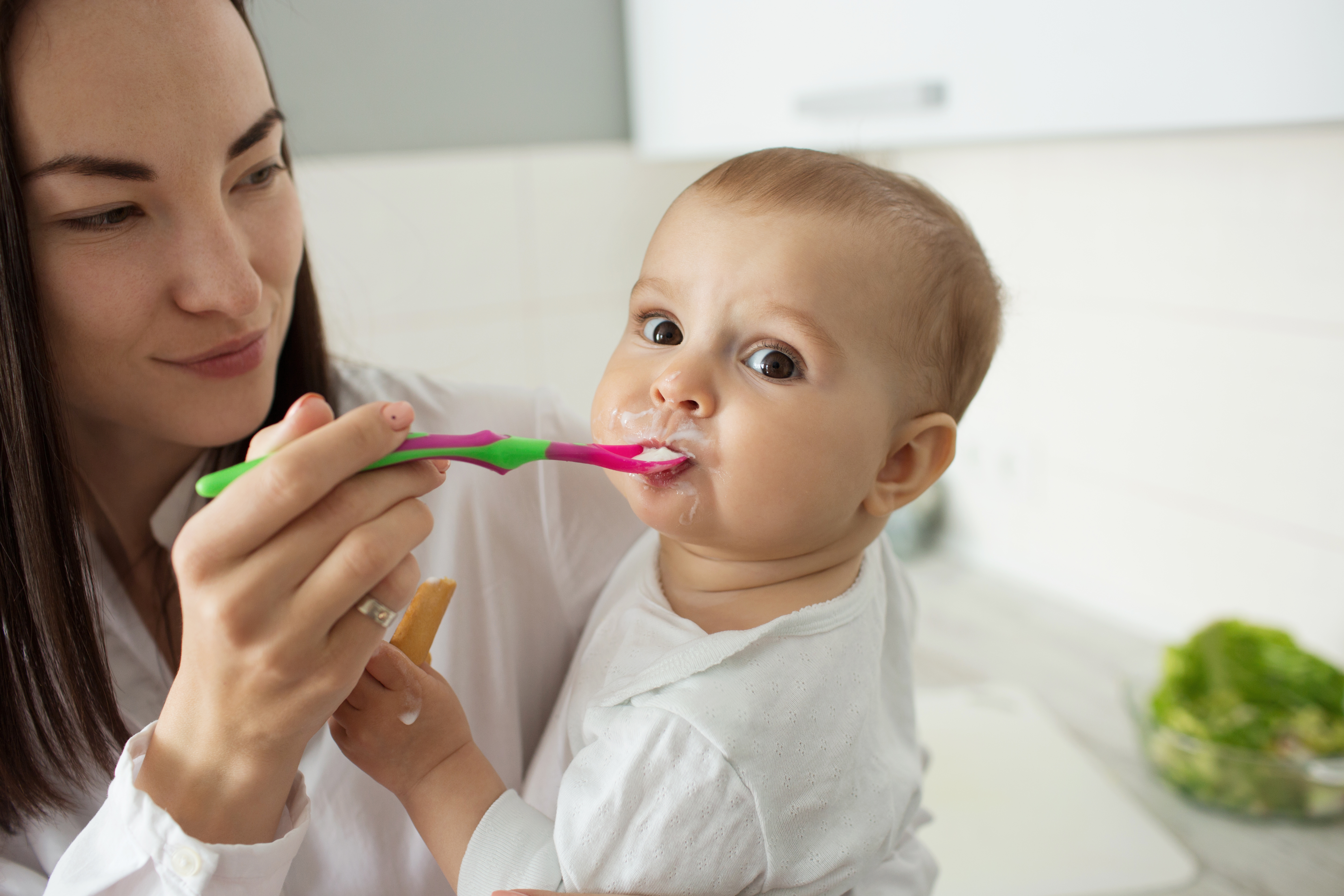 Mother feeding her baby with a spoon during the weaning stage
