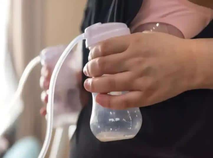 Mother hand-holding a breast pump while expressing milk